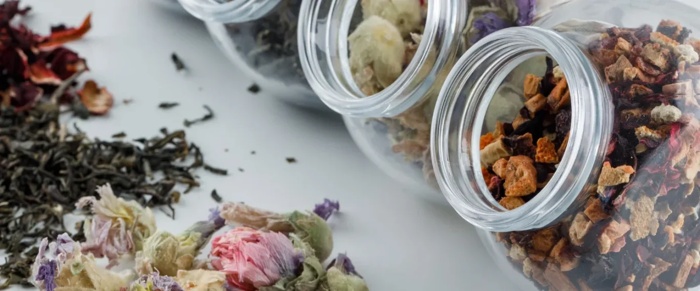 Assortiment de thé dans des bocaux en verre sur une surface claire.